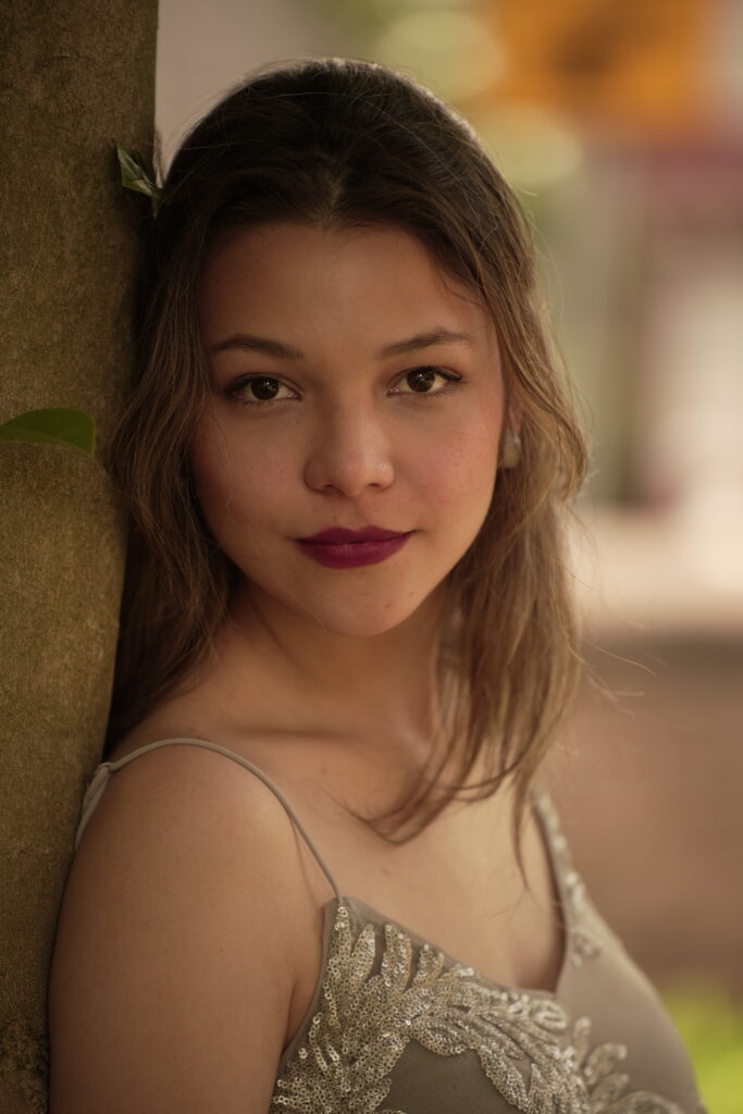 Lina standing in front of a blurred, natural background.